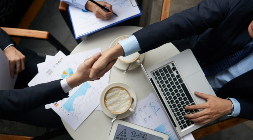 Imagem mostrando um empresário e um espacialista em marketing B2B trocando um aperto de mãos após fechar um negócio.