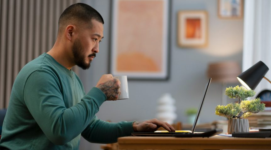 Imagem mostrando um homem que faz trabalho freelancer em sua casa, cumprindo suas demandas diárias enquanto toma um café.