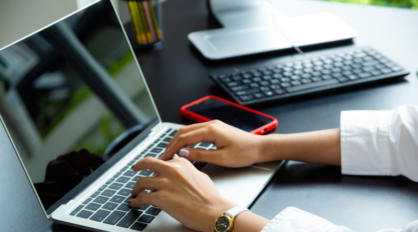Mulher digitando no teclado do notebook, trabalhando com produção de conteúdo