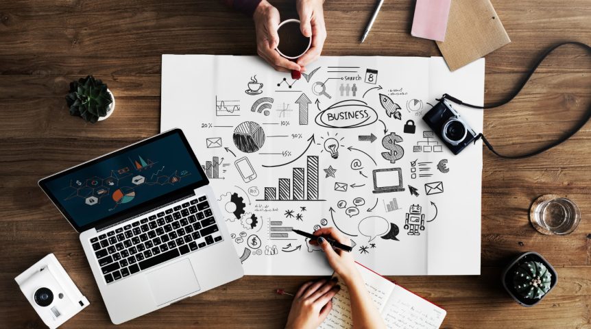 Imagem vista de cima mostrando dois profissionais analisando as métricas de marketing digital de sua empresa.