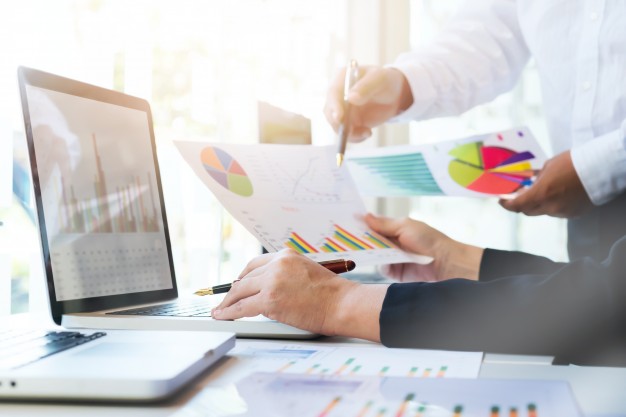 Analistas de marketing olhando planilhas e dados para calcular o retorno sobre investimento na estratégia.