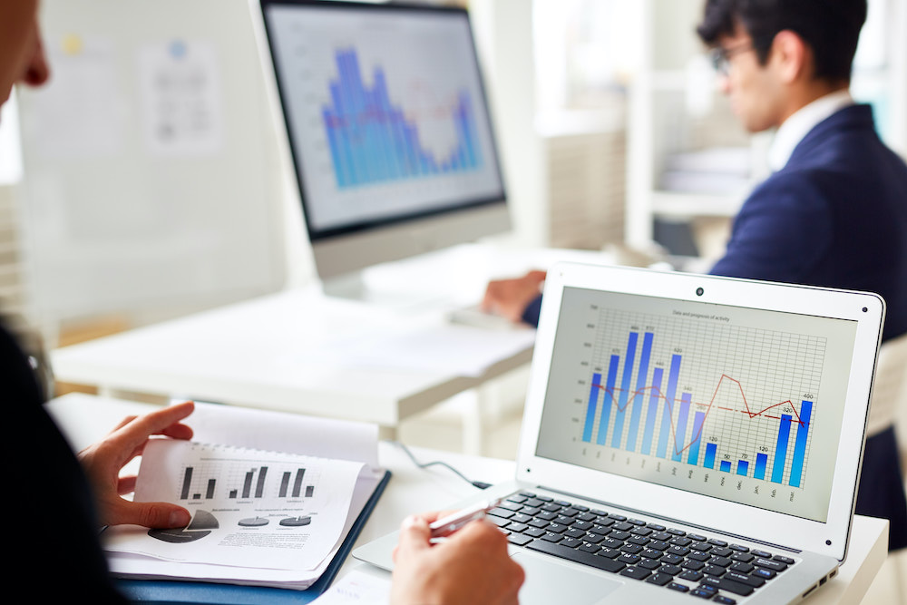 computadores exibindo dados e gráficos de um programa de gestão financeira