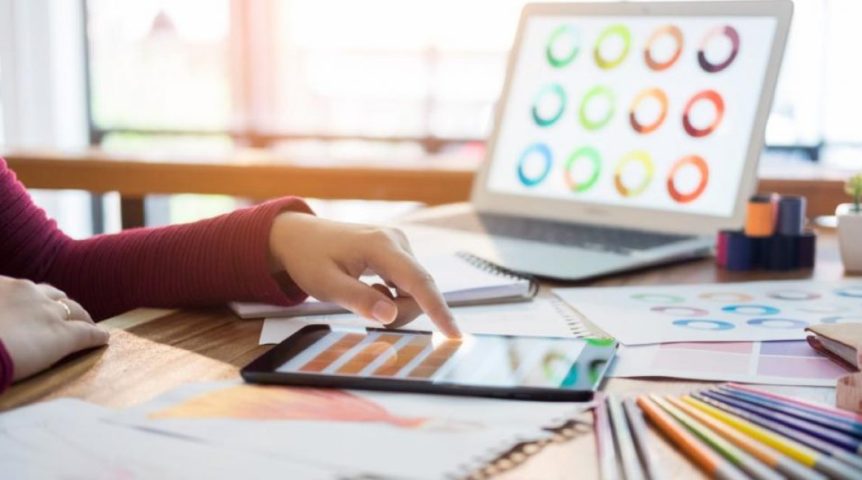 mulher trabalhando no tablet e no notebook, dando um exemplo de economia criativa
