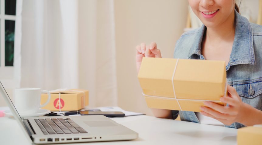 Beautiful smart Asian young entrepreneur business woman owner of SME online checking product on stock and save to computer working at home. Small business owner at home office concept.