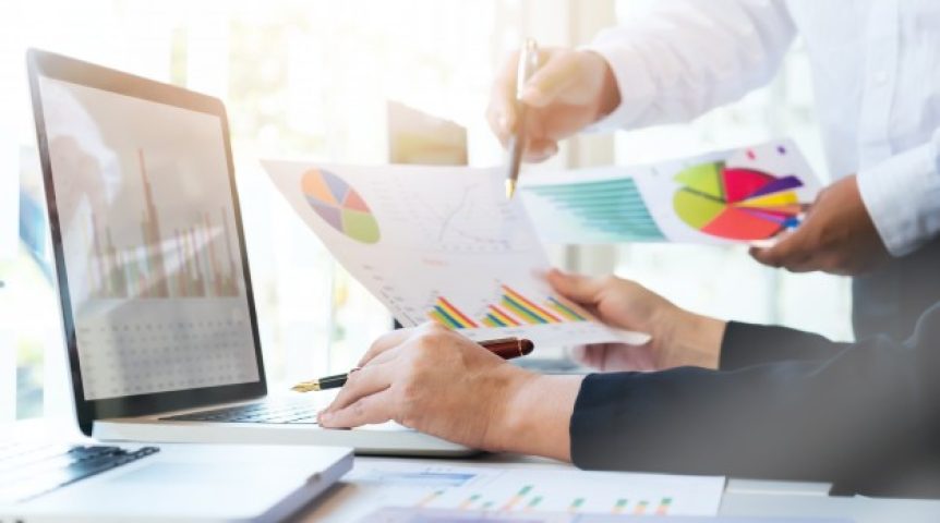 Analistas de marketing olhando planilhas e dados para calcular o retorno sobre investimento na estratégia.