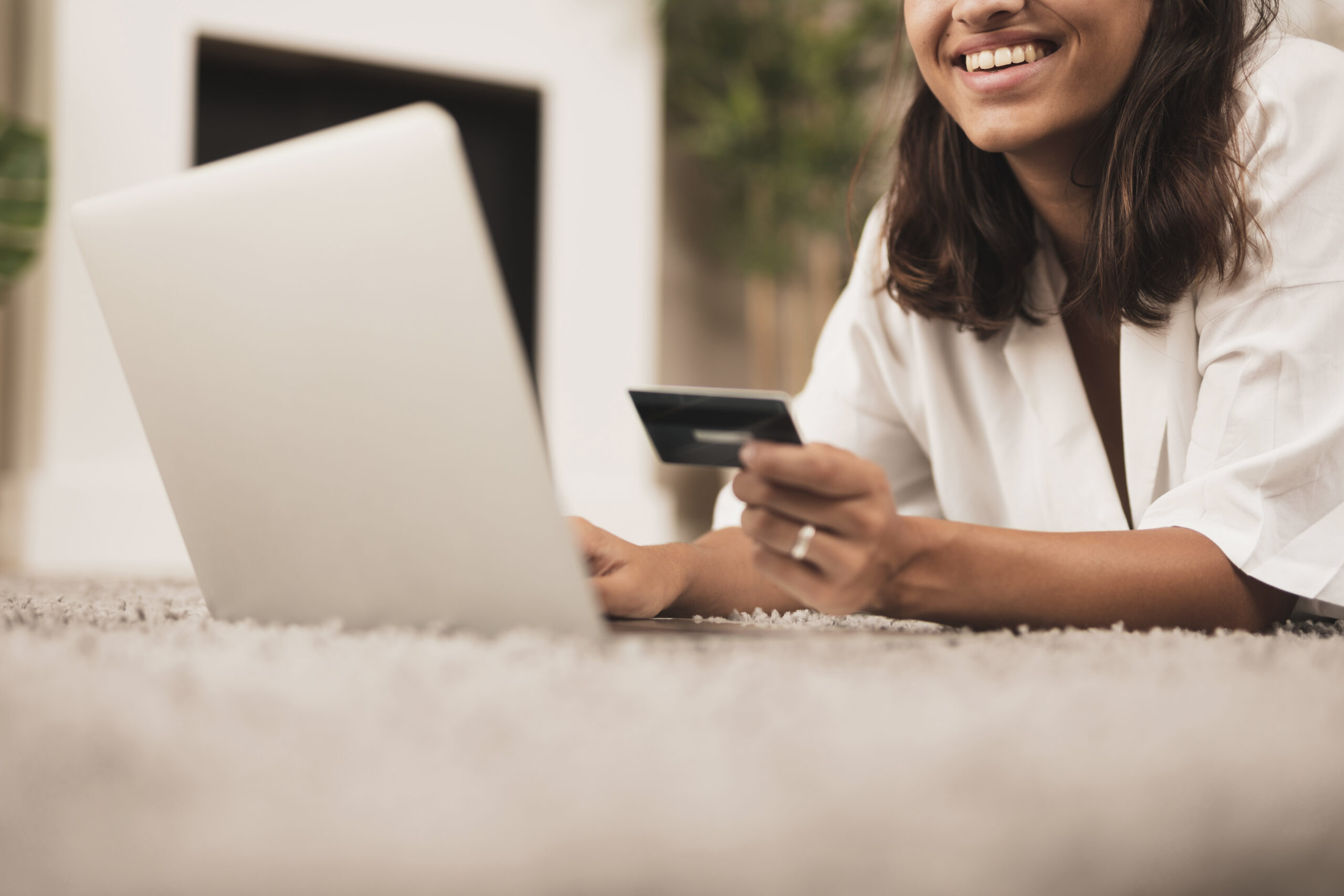 Mulher investindo em vendas online, sorrindo em frente ao computador.