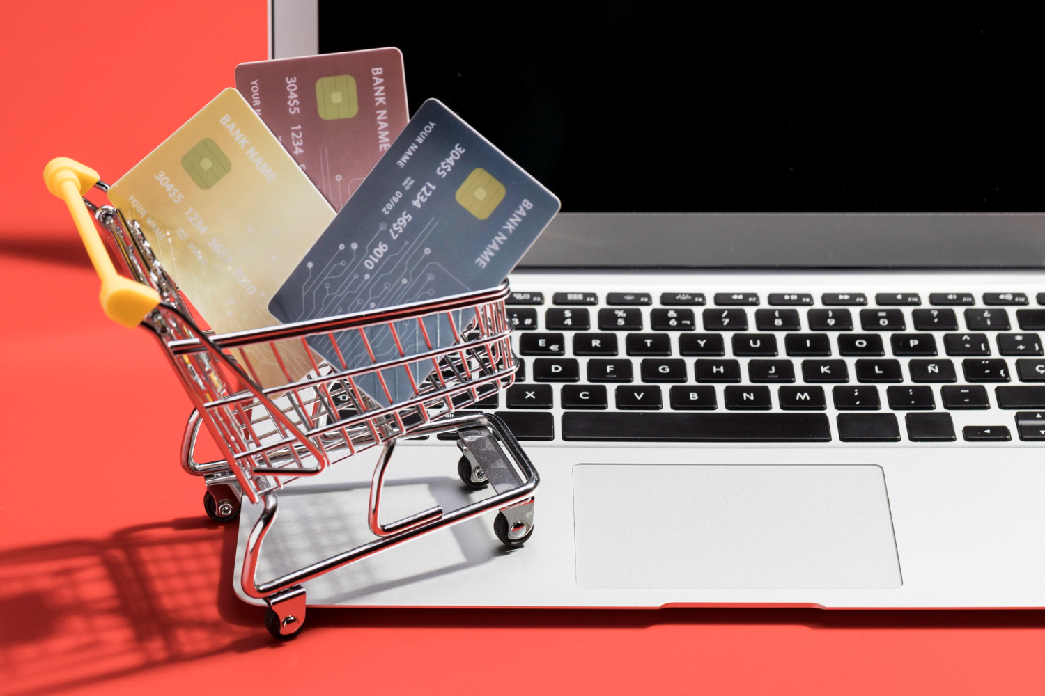 Imagem ilustrativa sobre criação de e-commerces em Curitiba, mostrando um carrinho de compras, cartões de crédito e um notebook.